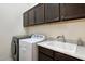 Laundry room boasts dark cabinets, sink, washer, and dryer at 12716 W Mclellan Rd, Glendale, AZ 85307