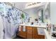 Well-lit bathroom featuring a double sink vanity and decorative shower curtain at 14547 W Evans Dr, Surprise, AZ 85379