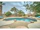 Relaxing pool area with rock waterfall feature, surrounded by lush landscaping and swaying palm trees at 14674 W Windsor Ave, Goodyear, AZ 85395