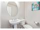 Stylish half-bathroom with a pedestal sink, round mirror, and modern fixtures at 15652 N 175Th Ct, Surprise, AZ 85388