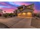 Elegant exterior view of a two-story home with a three-car garage, stone accents, and a spacious driveway at sunset at 15652 N 175Th Ct, Surprise, AZ 85388