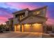 Elegant exterior view of a two-story home with a three-car garage, stone accents, and a balcony at sunset at 15652 N 175Th Ct, Surprise, AZ 85388