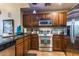 Kitchen featuring dark wood cabinets, stainless steel appliances, granite countertops, and a decorative backsplash at 1664 E Bridgeport Pkwy, Gilbert, AZ 85295