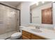 Bathroom with a tiled shower, wood vanity, and a large framed mirror at 19927 W Meadowbrook Ave, Litchfield Park, AZ 85340