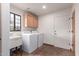 Laundry room with utility sink, front loading washer and dryer, and custom cabinets at 19927 W Meadowbrook Ave, Litchfield Park, AZ 85340