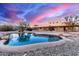 Backyard pool features a unique rock border and mountain views with an elegant stucco house in the background at 19927 W Meadowbrook Ave, Litchfield Park, AZ 85340