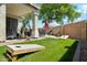 Inviting backyard with a covered patio, lawn, mature trees and a cornhole game at 20477 N 91St Dr, Peoria, AZ 85382
