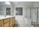 Well-lit bathroom featuring a dual vanity, tub and walk-in shower with glass block window at 20477 N 91St Dr, Peoria, AZ 85382