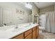 Bathroom featuring double sinks, white countertops, wood cabinets and a shower over tub at 20477 N 91St Dr, Peoria, AZ 85382