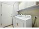 Bright laundry room features a washer and dryer, storage cabinets, and a door to the exterior at 20477 N 91St Dr, Peoria, AZ 85382