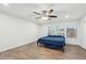 Cozy bedroom featuring a simple bed frame, blue comforter, hardwood floors, and natural light from two windows at 2472 W Hawks Eye Ave, Apache Junction, AZ 85120