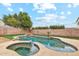 View of backyard pool with rock features, and spa surrounded by block fence and green landscaping at 2472 W Hawks Eye Ave, Apache Junction, AZ 85120