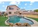 Backyard featuring a sparkling pool with rock features, lush turf, and covered patio of this desert home at 2472 W Hawks Eye Ave, Apache Junction, AZ 85120