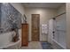 Well-decorated bathroom featuring a tub with shower, wood door, and unique wall art at 2729 W Dolores Rd, Phoenix, AZ 85086