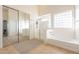 Bright bathroom with soaking tub, walk-in shower, and mirrored closet at 30402 W Vale Dr, Buckeye, AZ 85396