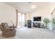 Cozy seating area with large windows, neutral carpet, TV, and recliner at 30402 W Vale Dr, Buckeye, AZ 85396