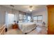 Spacious main bedroom with large windows, a ceiling fan, gray accent wall, and a wooden dresser and nightstand at 33732 N Sandstone Dr, San Tan Valley, AZ 85143