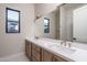 Modern bathroom with a double sink vanity, large mirror, and a view into the tiled shower at 37937 N 31St Ave, Phoenix, AZ 85086