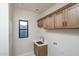 Bright laundry room with wooden cabinets, stainless steel sink, and natural light at 37937 N 31St Ave, Phoenix, AZ 85086