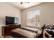 Well-lit bedroom featuring a wooden dresser, flatscreen TV, and comfortable striped bedding at 6589 E Casa De Leon Ln, Gold Canyon, AZ 85118