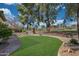 Beautifully landscaped backyard with a verdant lawn, mature trees, and a stone walkway at 800 W Palo Brea Dr, Litchfield Park, AZ 85340