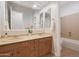 Well-lit bathroom with double sink vanity, large mirror, neutral tile, and shower-tub combo at 800 W Palo Brea Dr, Litchfield Park, AZ 85340