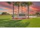 Sunland Village East Golf Club sign surrounded by manicured lawns and palm trees under a colorful sunset sky at 8012 E Monte Ave, Mesa, AZ 85209