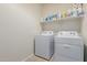 Well-lit laundry room featuring a washer and dryer, with shelving above for storage at 1021 W Descanso Canyon Dr, Casa Grande, AZ 85122