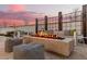 Elegant outdoor seating area with a stone fire pit, plush cushions, and a view of the beautiful backyard at dusk at 11143 N Mckinney St, Surprise, AZ 85388