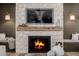 Close-up of a stone fireplace with a wooden mantle, built-in benches and decorative lighting at 11143 N Mckinney St, Surprise, AZ 85388