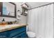 Bathroom featuring a blue vanity with granite countertop, wood shelves, and a shower with a white curtain at 1353 N Avoca --, Mesa, AZ 85207