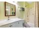 Bathroom with light green walls, shower-tub combo, mirror, and sink with white cabinets at 13633 N 111Th Ave, Sun City, AZ 85351