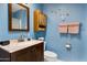 Cozy blue bathroom features a wood vanity, mounted cabinet, and nautical themed decor at 13633 N 111Th Ave, Sun City, AZ 85351