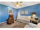 Bright living room features blue walls, a ceiling fan, sofa, and reclining chair at 13633 N 111Th Ave, Sun City, AZ 85351