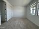 A bright bedroom with a large window, neutral carpeting, and closet with bi-fold doors at 15762 W Cheryl Dr, Waddell, AZ 85355