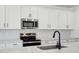 Modern kitchen with white cabinets, stainless steel appliances, quartz countertops, and tile backsplash at 15762 W Cheryl Dr, Waddell, AZ 85355