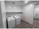 Convenient laundry room with a washer, dryer, storage shelf, and tile flooring at 15762 W Cheryl Dr, Waddell, AZ 85355