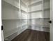 Walk-in pantry featuring wood-look flooring and plenty of white shelving for storage at 15762 W Cheryl Dr, Waddell, AZ 85355