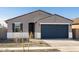 Charming single-story home featuring a gray stucco exterior, dark blue garage door and desert landscaping at 15993 W Cottontail Ln, Surprise, AZ 85387