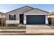 Charming single-story home featuring a gray stucco exterior, dark blue garage door and desert landscaping at 15993 W Cottontail Ln, Surprise, AZ 85387