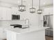 Modern kitchen featuring white cabinets, stainless steel appliances, and stylish pendant lighting over the island at 15993 W Cottontail Ln, Surprise, AZ 85387