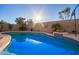 Sparkling pool with decorative tile, set against a backdrop of mature trees and a sunny sky at 16412 N 168Th Ln, Surprise, AZ 85388