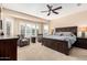 Spacious main bedroom features a ceiling fan, neutral carpet, plantation shutters, and a decorative accent wall at 16713 W Monte Vista Rd, Goodyear, AZ 85395