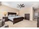 Bedroom features a ceiling fan, plush neutral carpet, and wood furnishings for a warm atmosphere at 16713 W Monte Vista Rd, Goodyear, AZ 85395