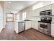 Open kitchen with wood floors, white cabinets, stainless steel appliances, and an island sink at 17441 W Rock Ledge Rd, Goodyear, AZ 85338