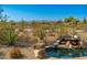 Close up of rock waterfall feature flowing into the pool with desert plants and mountain views at 19460 N 84Th St, Scottsdale, AZ 85255