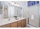 Well-lit bathroom featuring double sinks, a large mirror, and a glass-enclosed shower at 21511 N 79Th Dr, Peoria, AZ 85382