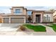 Inviting two-story home featuring a manicured lawn, stone accents, and an attached three-car garage at 21732 N 86Th Ln, Peoria, AZ 85382