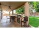 Covered outdoor kitchen area with built-in grill and seating overlooks lush backyard at 21732 N 86Th Ln, Peoria, AZ 85382