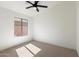 A bright bedroom with a ceiling fan and a window overlooking the backyard at 21824 N 32Nd Ave, Phoenix, AZ 85027